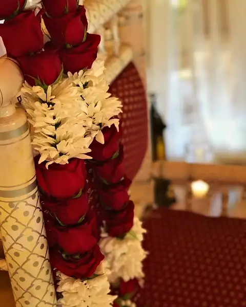 Fresh red rose and white bloom jaimala garland draped over a carved wedding chair