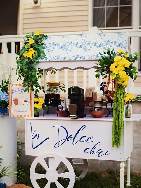 Custom chai cart decorated with yellow roses, hanging green amaranthus and blue florals at a backyard haldi