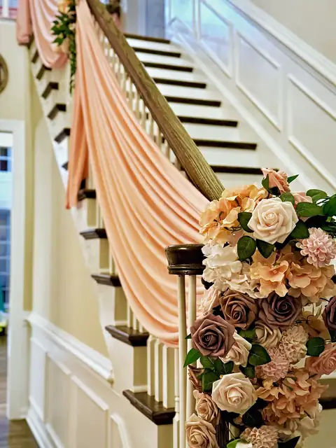 Peach chiffon draping and a blush rose garland cascading down a staircase for an at-home celebration
