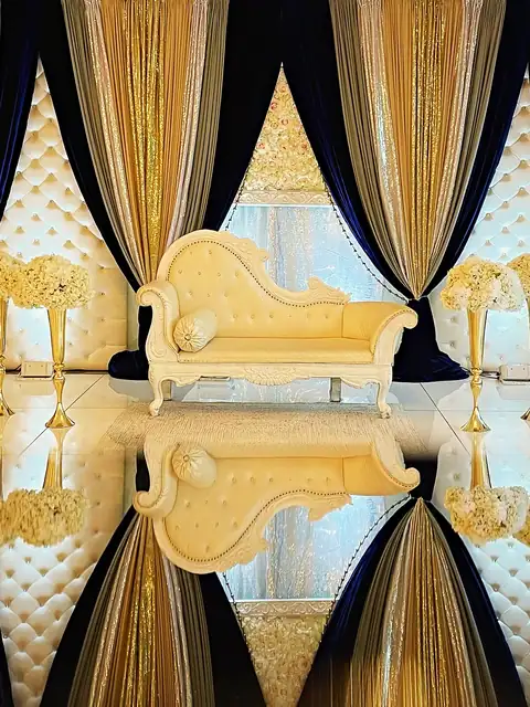 Ivory chaise reflected on a mirror floor stage framed by navy velvet and gold sequin drapes